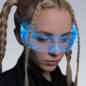 May include: Futuristic blue-light glasses with a sleek, transparent design. The glasses feature illuminated circuitry patterns and a glowing blue light, creating a high-tech aesthetic. The overall design suggests a cyberpunk or sci-fi theme.
