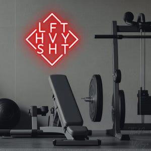 Peut inclure: Une enseigne néon rouge fixée au mur, en forme de losange avec les lettres LFT, HVY et SHT disposées en grille à l'intérieur. L'enseigne émet une lueur rouge vive, présentant une typographie sans empattement nette dans le cadre géométrique.