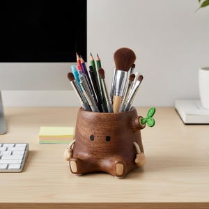 Könnte beinhalten: Ein skurriler Schreibtisch-Organizer aus braunem Holz in Form eines Baumstumpfes, der verschiedene Stifte, Bleistifte und Make-up-Pinsel enthält. Der Organizer hat ein niedliches Gesicht, kleine Arme und Beine. Ein grünes Blatt sprießt von der Seite.