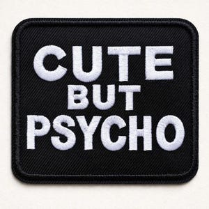 Könnte beinhalten: Ein schwarzer, quadratischer Aufnäher mit weiß gesticktem Text "CUTE BUT PSYCHO". Der Aufnäher hat einen schwarzen Rand und ist zum Aufnähen oder Aufbügeln auf Kleidung oder Accessoires gedacht. Der Text ist in einer fetten, serifenlosen Schriftart.