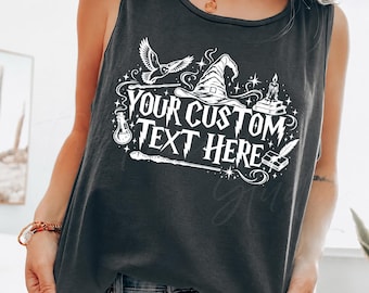 May include: A charcoal gray sleeveless tank top featuring a white graphic print with the text "YOUR CUSTOM TEXT HERE". The design includes a wizard hat, an owl, a candle, a potion bottle, a wand, and a quill with an open book, all surrounded by stars.