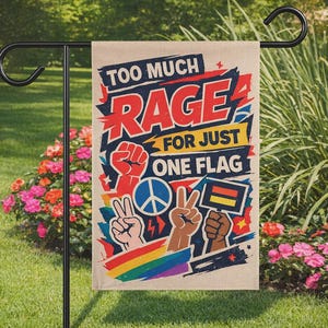 Op de afbeelding: Een beige tuinvaandel met de tekst "TOO MUCH RAGE FOR JUST ONE FLAG" in rood en blauw. De vlag toont illustraties van een vuist, vredestekens, een regenboog en een Duitse vlag.