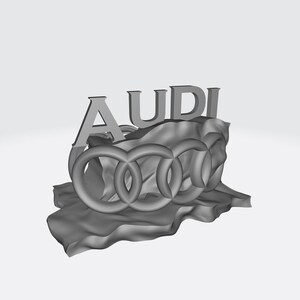 May include: A gray 3D rendering of the Audi logo, featuring the word "AUDI" above the four interlocking rings. The logo is set on a textured, wave-like surface, all against a white background.