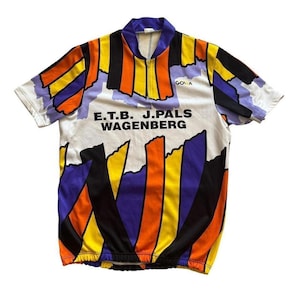 May include: White cycling jersey with a colorful abstract design featuring orange, yellow, black, and purple vertical stripes. The jersey has a zipper and the text "E.T.B. J.PALS WAGENBERG" printed on the front.