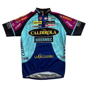 Könnte beinhalten: Ein Vintage-Radtrikot in Blau, Hellblau und Lila. Das Trikot zeigt Sponsorenlogos und den Text "CALDIROLA" und "SIDERMEC". Es hat einen Reißverschluss am Kragen und kurze Ärmel.