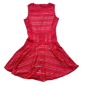 K&ouml;nnte beinhalten: Ein &auml;rmelloses rotes Spitzenkleid mit Rundhalsausschnitt, einem figurbetonten Oberteil mit horizontalen Cut-out-Details und einem ausgestellten Rock. Das Kleidungsst&uuml;ck besteht aus texturierter Blumenspitze mit einem Muster aus Lochstreifen.