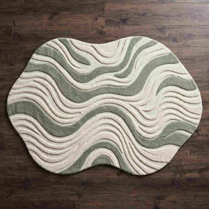 May include: An irregularly shaped area rug featuring a textured, wavy pattern in alternating bands of sage green and cream. The rug has a tufted, high-low pile construction that creates a dimensional, flowing design across the entire surface.