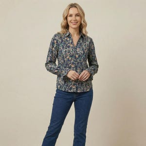Può includere: Camicia a maniche lunghe con stampa floreale blu navy. La camicia è abbottonata e indossata con jeans blu. La donna sorride.
