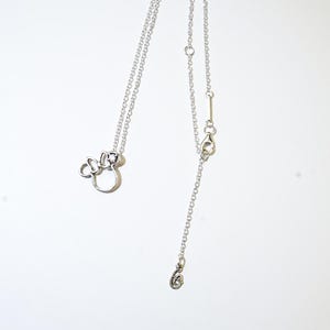 Puede incluir: Un collar plateado con un colgante de lazo de Minnie Mouse. El collar tiene una cadena fina con una longitud ajustable y un cierre de mosquet&oacute;n. El colgante es un contorno estilizado del ic&oacute;nico lazo de Minnie Mouse.