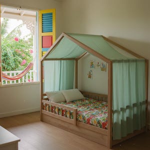 Puede incluir: Una cama de madera con forma de casa con dosel y cortinas verde claro. La cama tiene una colcha con estampado floral colorido y dos almohadas blancas. La habitación tiene una ventana con una hamaca y contraventanas coloridas.