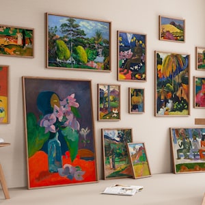Peut inclure: Une collection d'impressions d'art encadrées, présentant des peintures colorées avec des paysages, des figures et des natures mortes. Les œuvres sont exposées sur un mur neutre, créant une ambiance de galerie. Des tabourets en bois et une table sont au premier plan.