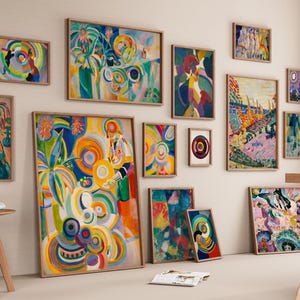May include: A collection of framed abstract paintings in various sizes and styles, displayed on a neutral wall. The artworks feature vibrant colors and swirling patterns, creating a gallery-like atmosphere. Wooden stools and a table are in the foreground.