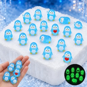 May include: A collection of small, translucent blue penguin figurines with white bellies and orange beaks. Some penguins feature a red heart on their chest, while others are shown in a glowing green state in a circular inset image.