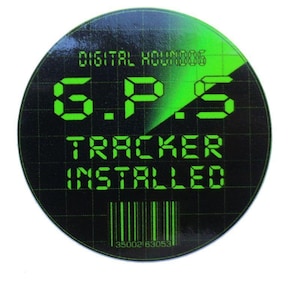 Może przedstawiać: Okrągła czarna naklejka z zielonym tekstem i zielonym wzorem przypominającym radar. Tekst brzmi "DIGITAL HOUNDOG", "G.P.S TRACKER INSTALLED" oraz kod kreskowy na dole. Naklejka ma błyszczące wykończenie.