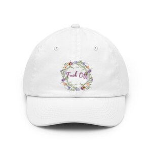 Könnte beinhalten: Weiße Baseballkappe mit floralem Kranz-Design und dem Text "Fuck Off". Der Kranz enthält lila, orange und gelbe Blumen mit grünen Blättern. Die Kappe hat einen gebogenen Schirm.
