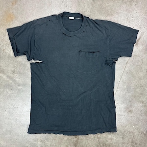 May include: A distressed black t-shirt with a crew neck and a single pocket on the chest. The shirt has a worn appearance with holes and tears, giving it a vintage or grunge aesthetic. The fabric appears soft and well-worn.