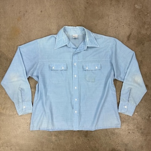 May include: Light blue button-down shirt with two chest pockets and a pointed collar. The long-sleeved shirt has white buttons and cuffs. The shirt is made of a light-weight fabric and has a vintage look.