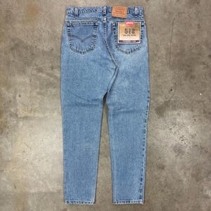 May include: Light blue Levi's 512 tapered leg jeans. The jeans have a classic five-pocket design, a faded wash, and a Levi's brand patch on the back. The tag reads "512" and "Tapered Leg".