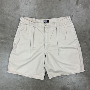 May include: Khaki-colored shorts with a pleated front. The shorts have a button closure and belt loops. The Polo by Ralph Lauren logo is visible on the back. The shorts are made of a durable fabric.