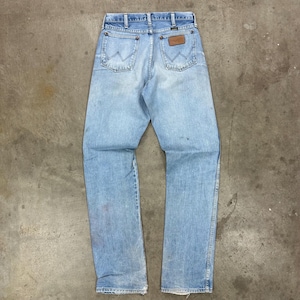 Op de afbeelding: Lichtblauwe denim jeans met een klassiek ontwerp met vijf zakken. De jeans hebben een bruine leren patch op de achterkant en het Wrangler-logo. De jeans zijn vintage en vertonen gebruikssporen.