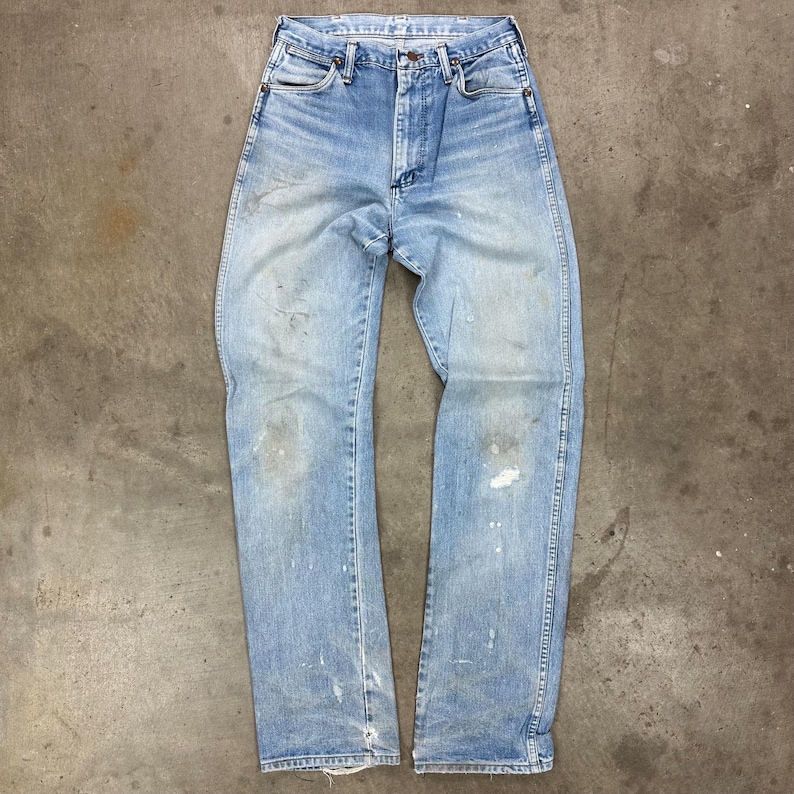 Op de afbeelding: Lichtblauwe denim jeans met een vervaagde wassing en verfspetters. De jeans hebben een klassiek ontwerp met vijf zakken, een knoop- en ritssluiting en een rechte pijp. De jeans zijn versleten en hebben distressed details.