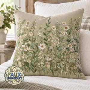May include: A square throw cushion featuring a light sage green fabric base with detailed embroidery of various wildflowers, including white daisies and green foliage. The design covers the front surface with a dense, botanical meadow pattern.