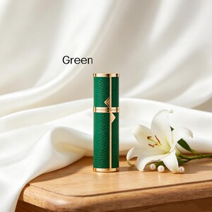 K&ouml;nnte beinhalten: Ein gr&uuml;ner Parf&uuml;mzerst&auml;uber mit goldenen Akzenten. Die zylindrische Flasche hat eine strukturierte Oberfl&auml;che und ist mit "Green" beschriftet. Eine wei&szlig;e Lilie und Perlen liegen neben der Flasche auf einer Holzoberfl&auml;che.