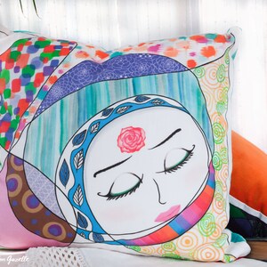 May include: A colorful pillow with a stylized illustration of a woman's face with closed eyes. The pillow is made of fabric and has a patchwork design with geometric shapes and swirls.