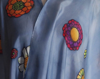 May include: A light blue silk scarf with a floral design. The flowers are in shades of red, orange, yellow, green, purple, and white. The scarf has the text "Salon Gazelle" in the bottom right corner.