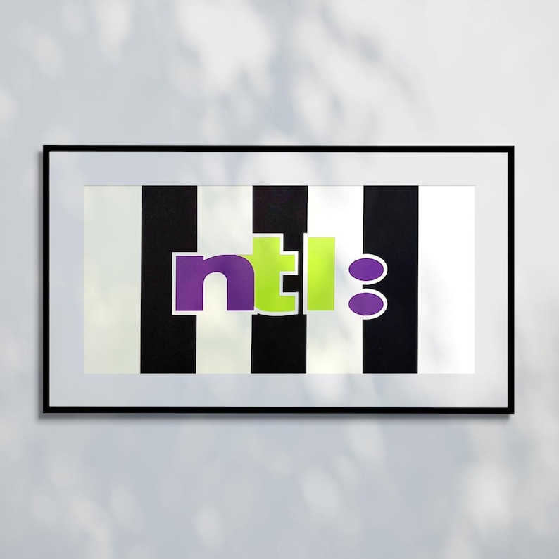 May include: Framed artwork with a black frame. The artwork features a black and white striped background with the letters "ntl:8" in purple and green. The artwork is rectangular and hangs on a white wall.