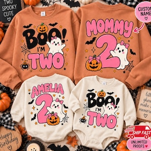 May include: Two orange sweatshirts and two cream-colored bodysuits featuring Halloween graphics. The designs include ghosts with pink bows, pumpkins, bats, and spiders. Text includes 'BOO I'M TWO', 'MOMMY 2', and the name 'AMELIA' with the number 2.