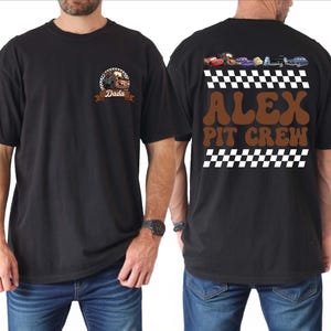 May include: A black t-shirt featuring a front graphic of a brown tow truck character with the text Dada. The back displays a row of colorful cartoon cars above a checkered pattern, with the brown text ALEX PIT CREW and another checkered border.
