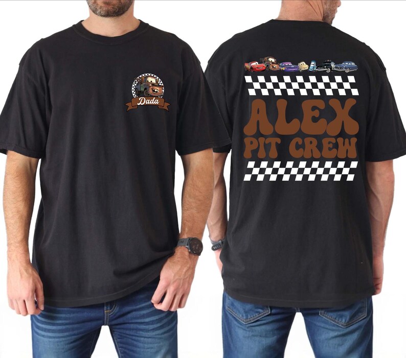 May include: A black t-shirt featuring a front graphic of a brown tow truck character with the text Dada. The back displays a row of colorful cartoon cars above a checkered pattern, with the brown text ALEX PIT CREW and another checkered border.