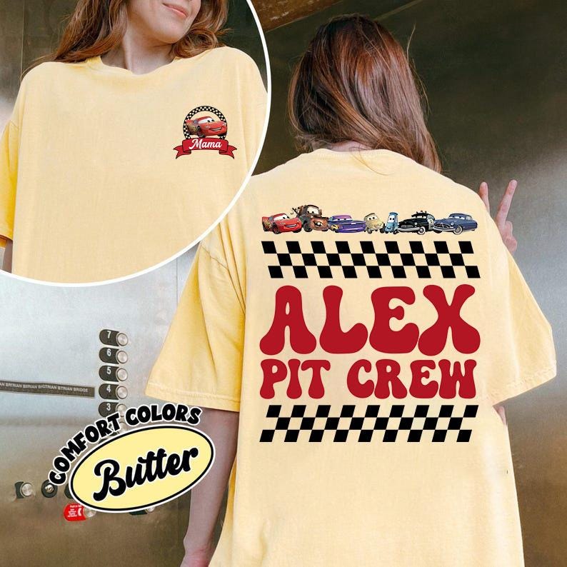 May include: A butter yellow t-shirt featuring a small graphic on the front chest of a red race car with the text Mama. The back displays a row of cartoon race cars above a black and white checkered pattern and the red text ALEX PIT CREW.