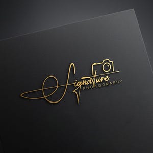 Könnte beinhalten: Goldenes "Signature Photography" Logo auf schwarzem Hintergrund. Das Logo zeigt einen kursiven Text mit einem Kamera-Symbol. Das Wort "Photography" steht kleiner unter "Signature".