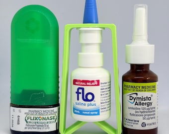 May include: Three nasal spray bottles: a Flixonase bottle with a green cap, a Flo saline plus bottle in a green plastic stand with a blue nozzle, and a brown Dymista Allergy bottle with a white nozzle. Each bottle features clear product labels.