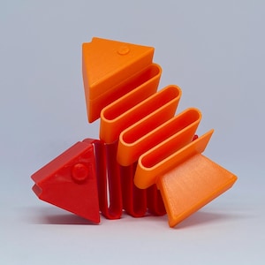 Peut inclure: Une sculpture de poisson imprimée en 3D en rouge et orange. Le poisson a une tête et une queue triangulaires, avec une série de côtes incurvées orange. La sculpture est en plastique et a une finition lisse. Le poisson est un objet décoratif.