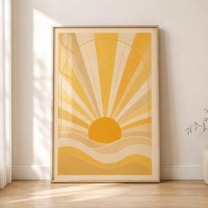 Pode incluir: Uma impressão de arte de parede retangular vertical apresentando um sol estilizado nascendo sobre colinas onduladas em camadas. O design usa uma paleta de tons amarelos, dourados e creme, com raios solares radiantes dentro de um arco fino.