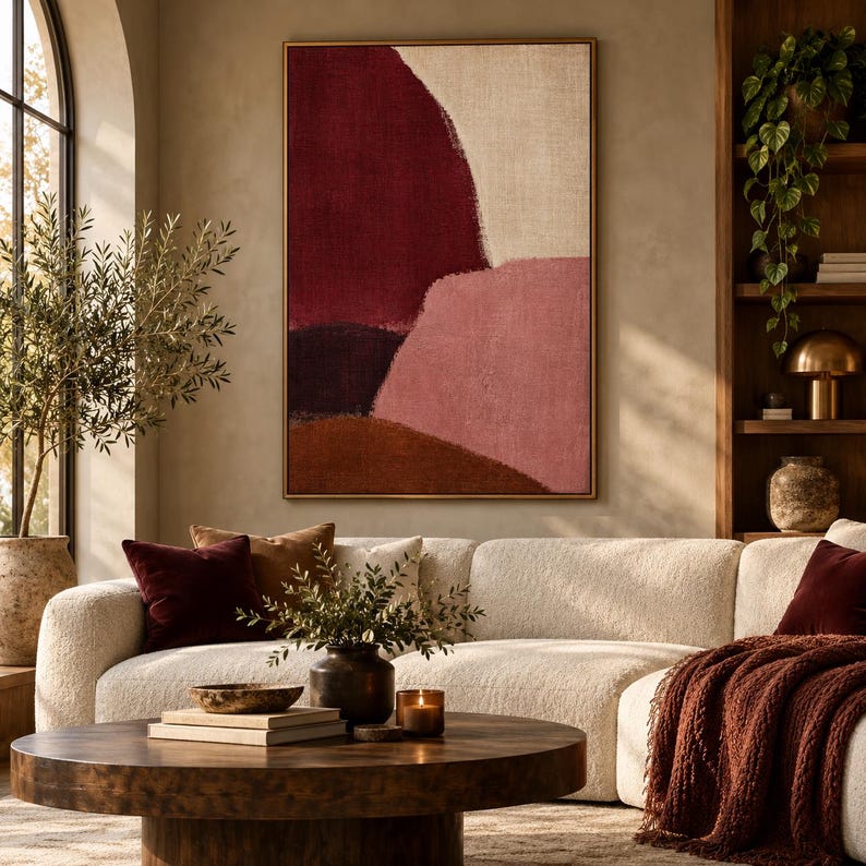 May include: A rectangular wall art piece featuring abstract color blocks in deep burgundy, soft pink, dark purple, and earthy brown, framed in a thin gold border. The composition displays textured, organic shapes on a neutral beige canvas background.