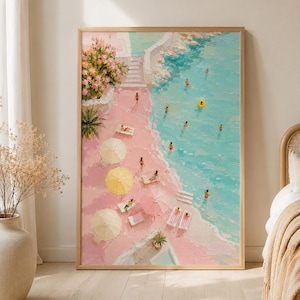 以下が含まれることがあります： 明るい木製のフレームに入った油絵で、ピンク色の砂浜、ターコイズブルーの海、泳ぐ人々が描かれた海岸の風景。ビーチには白と黄色のパラソル、ラウンジチェア、石段の近くにピンクの花が配置されています。
