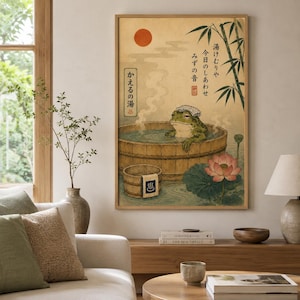 K&ouml;nnte beinhalten: Ein vertikaler Wandkunstdruck, der einen gr&uuml;nen Frosch mit einem wei&szlig;en Handtuch auf dem Kopf zeigt, der in einem Holzzuber badet. Die Illustration enth&auml;lt eine rote Sonne, Bambusstangen, eine rosa Lotusbl&uuml;te und japanische Schriftzeichen.
