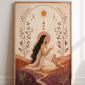 Op de afbeelding: Een ingelijste kunstdruk met een knielende figuur met lang donker haar die een gloeiende bol vasthoudt. De illustratie bevat een zon, maanfasen en boogvormige florale elementen in tinten van crème, terracotta en dieppaars.
