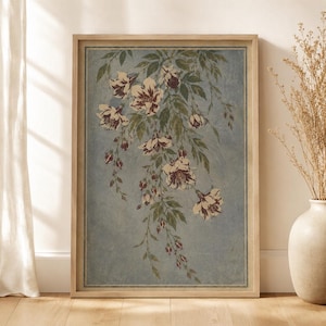 May include: A framed wall art print featuring a botanical illustration of cascading flowers with dark red and white petals and green leaves against a textured, dusty blue background. The artwork is enclosed in a light-toned wooden frame.