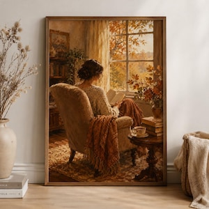 Könnte beinhalten: Ein gerahmter Kunstdruck, der eine Person in einem beigen Sessel an einem Fenster beim Lesen eines Buches zeigt. Die Szene besticht durch warme Herbstfarben, einen hölzernen Beistelltisch mit einer Teetasse und gestapelten Büchern.