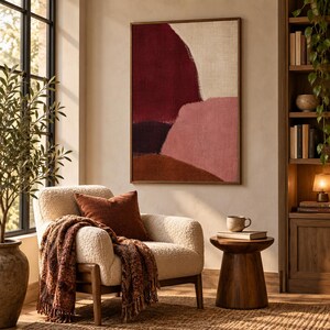 May include: A rectangular wall art piece featuring abstract shapes in deep burgundy, muted pink, and dark brown tones, framed in a thin wood border. The artwork displays a textured surface with layered color blocks and organic, curved edges.