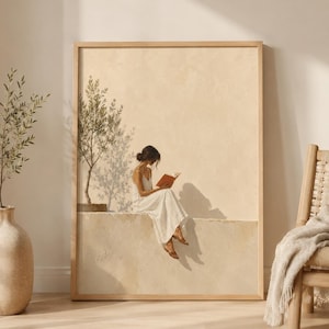 Op de afbeelding: Een ingelijste wandkunstprint met een schilderij van een persoon in een witte jurk die op een richel zit en een boek leest naast een olijfboom. De scène is uitgevoerd in warme beige en crèmetinten met zachte schaduwen op een getextureerde muur.