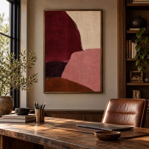 May include: A rectangular wall art piece featuring abstract shapes in deep burgundy, muted beige, dusty rose, and dark brown. The composition has a textured appearance with visible brushstrokes and is enclosed in a thin, metallic frame.