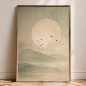 Può includere: Una stampa artistica incorniciata che raffigura un paesaggio dai toni tenui con dolci colline verdi, uno specchio d'acqua calmo e un grande sole circolare pallido nel cielo. Uno stormo di piccoli uccelli neri vola al centro della scena.