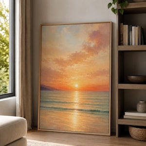 Op de afbeelding: Een rechthoekig ingelijst kunstwerk aan de muur met een olieverfschilderij van een zonsondergang boven de oceaan. De scène toont een felle zon laag aan de horizon, die gouden licht werpt over het water en het zandstrand, met zachte roze wolken.