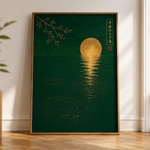 Puede incluir: Una impresión artística enmarcada representa una luna dorada que se refleja en agua verde oscuro. Los detalles dorados incluyen una rama y texto japonés. La obra de arte está en un marco dorado y se exhibe sobre un suelo de madera.